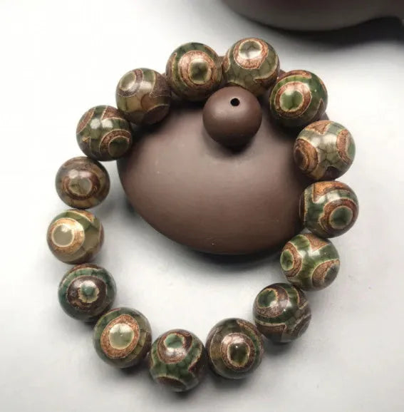 Natural agate men's bracelet with 14mm green three-eye round beads on a neutral background