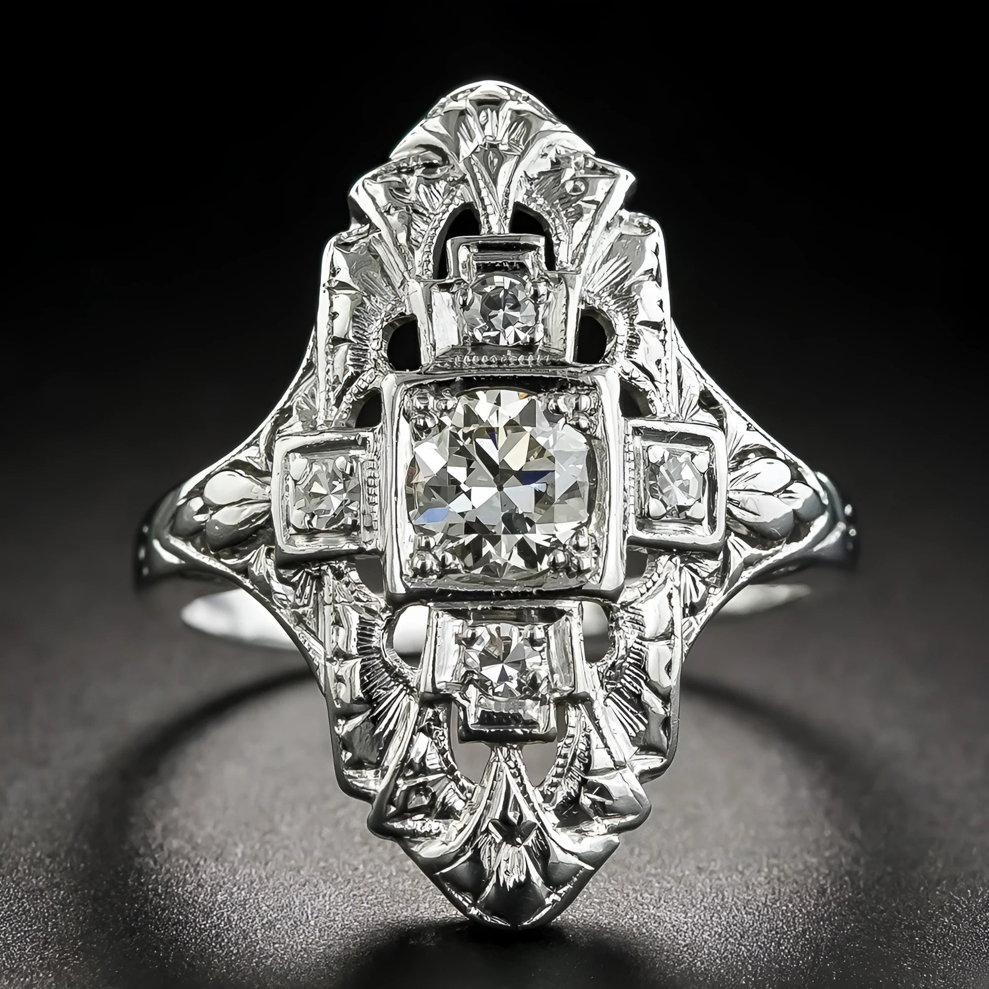 Geometric hollow-out silver ring with diamond studs on a finger.