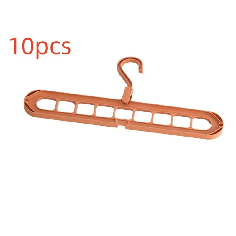 Green plastic folding clothes hanger with nine holes for organising trousers on a rack.
