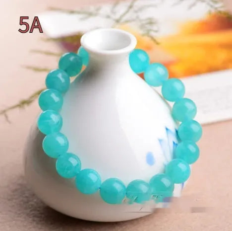 Natural blue-green Amazonite polished beads scattered on a surface, with a finished crystal bracelet.