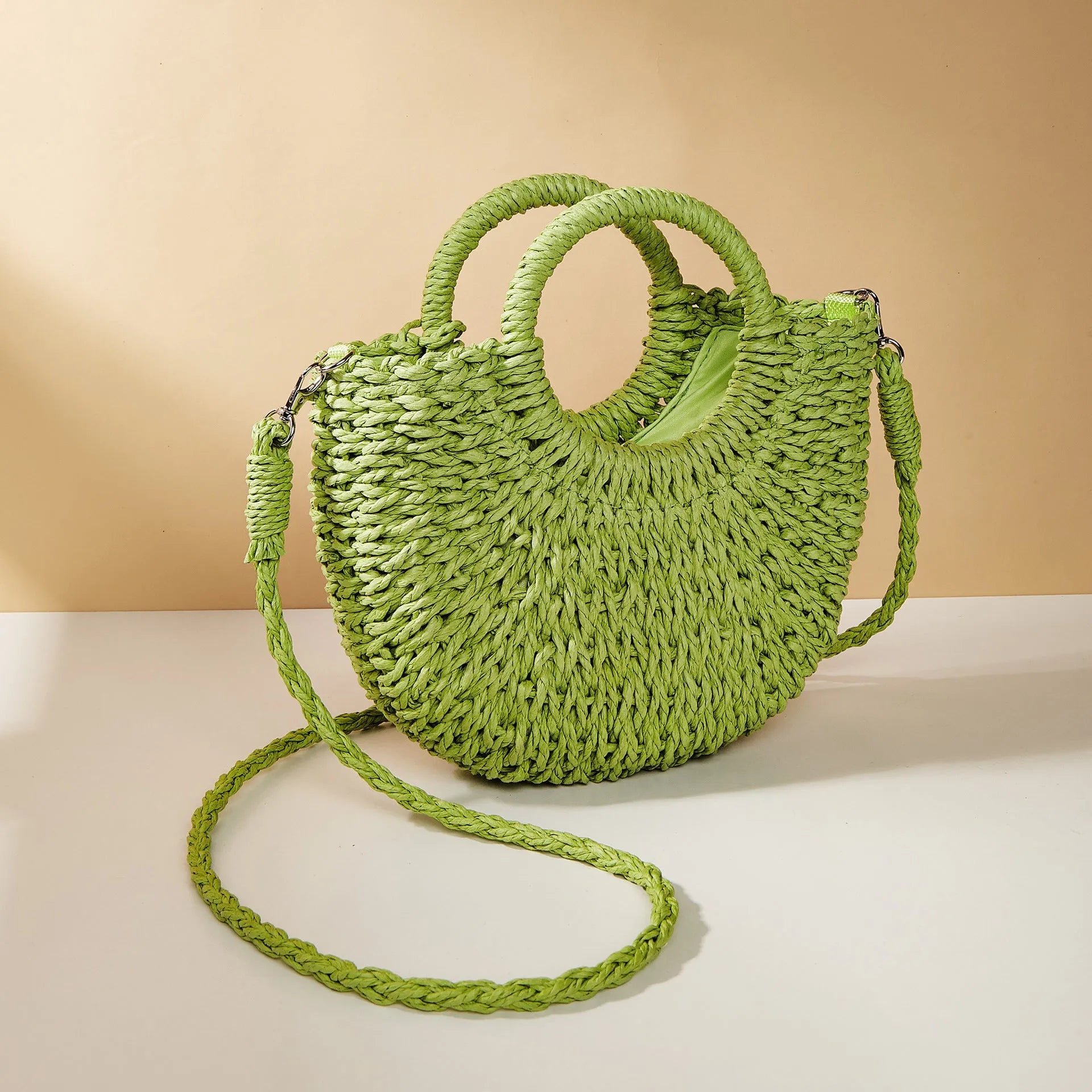Woven straw beach bag in beige, peach skin lining, crossbody style, 24cm height, on a sandy beach