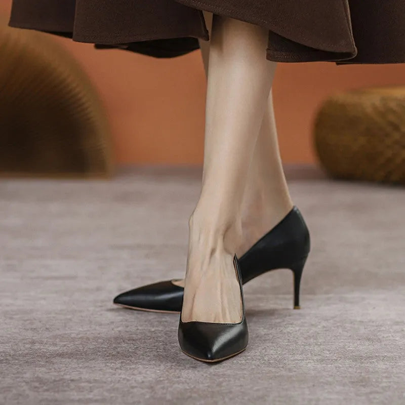 Black pointed toe stiletto high heel pump shoe with a low cut, shown on a white background.