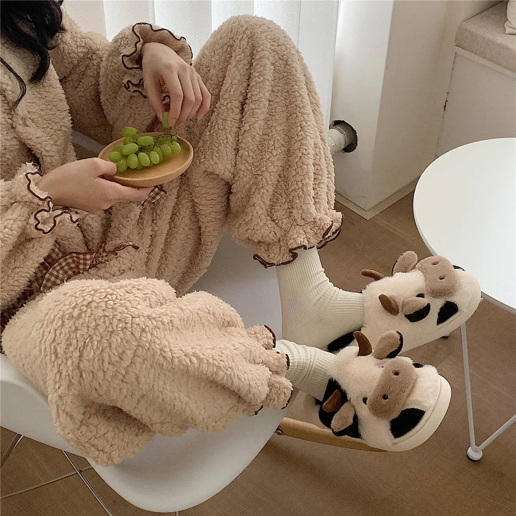 White cartoon cow design faux fur slippers for women with a non-slip textured sole.