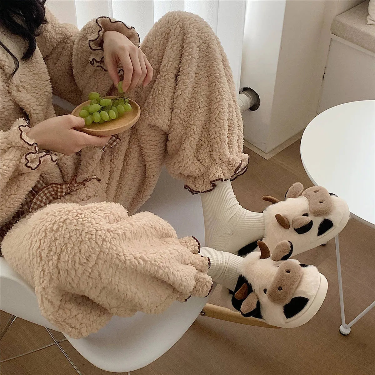 White cartoon cow design faux fur slippers for women with a non-slip textured sole.