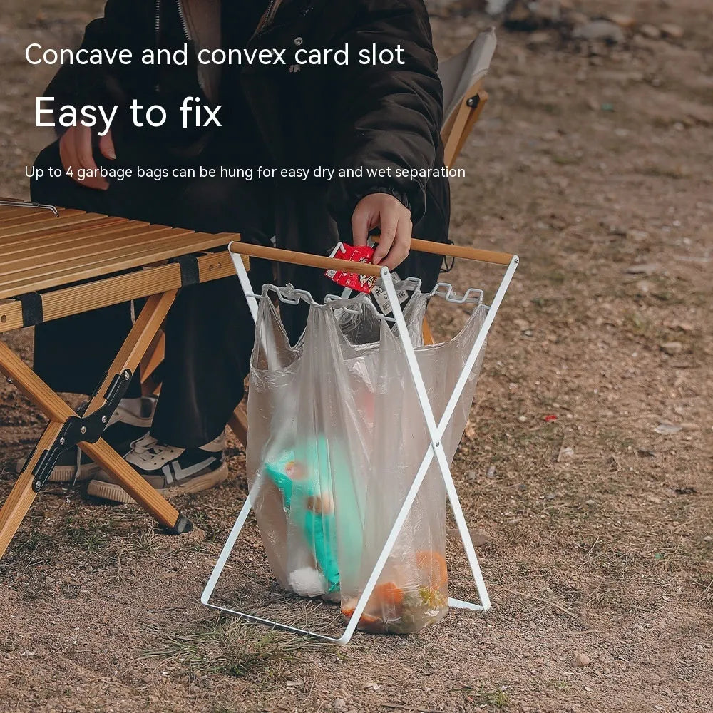 Black outdoor folding iron trash rack with a wooden handle, holding a bin bag.