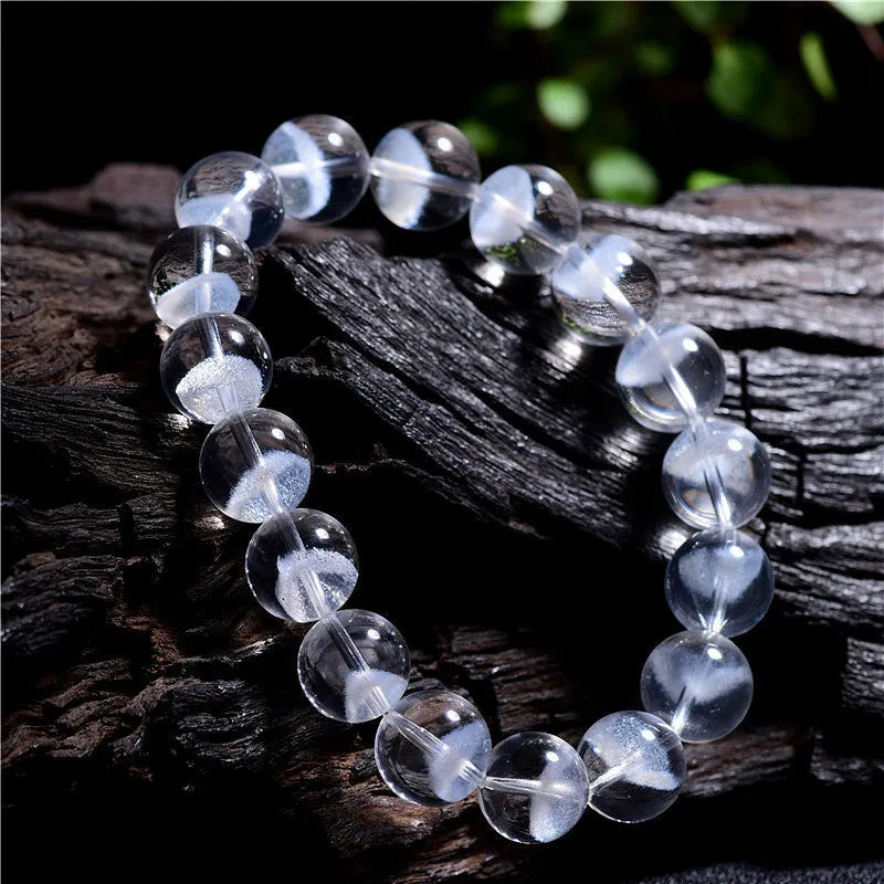 Women's white crystal bracelet with a ghost pyramid charm and Ruyi symbol, showing round beads.