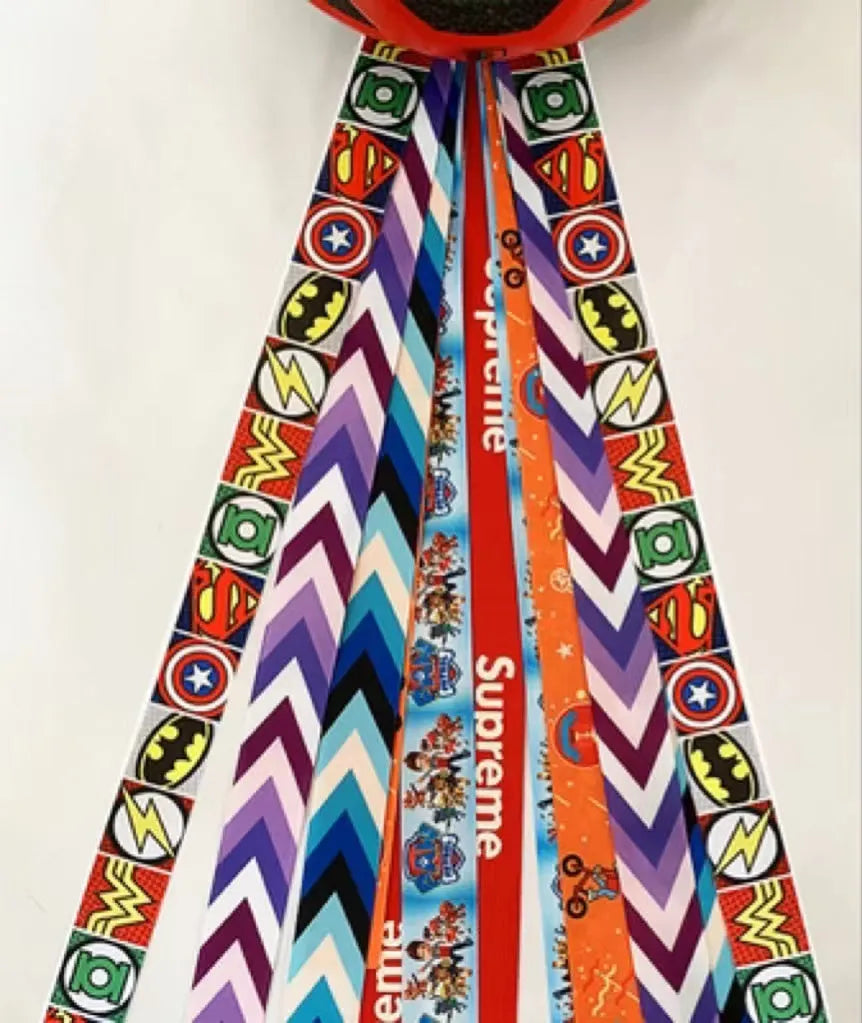 Colourful fabric helmet streamers for children's roller skating and ski helmets, shown in apricot, red, and grey.