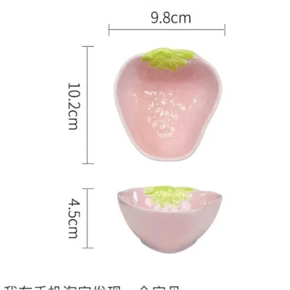 Cute strawberry pattern porcelain dinnerware set showing bowl, plate, and twist spoon on a table.