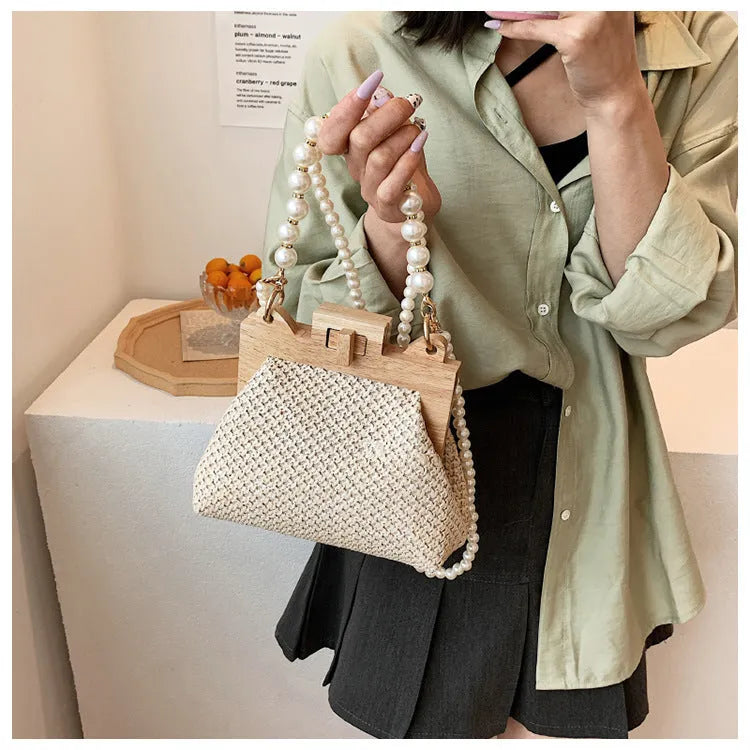 Women's woven straw shoulder bag with pearl chain detailing in horizontal square shape showing internal compartments