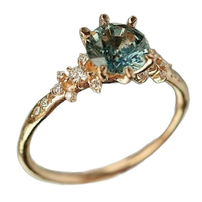 Gold geometric ring with claw settings holding zircon stones, showing chamfered square patterns on band