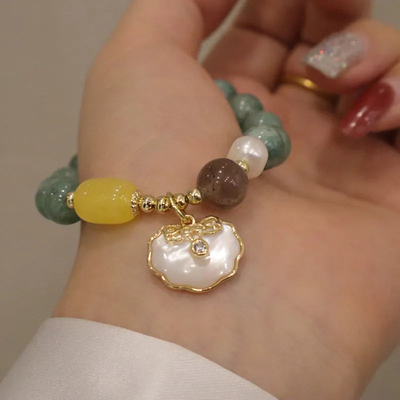 Green jade shell bracelet with adjustable silver chain on a wrist.