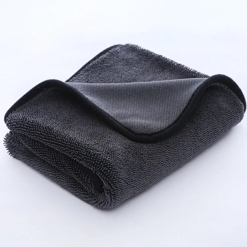 Grey braided car cleaning towel with red edge trim shown drying a car windscreen.