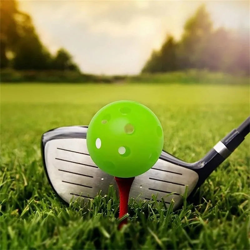 Six coloured 42mm golf practice balls in red, orange, blue, green, white and yellow arranged on putting surface
