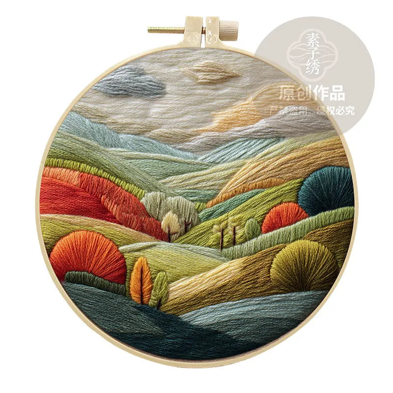 Embroidery DIY kit with bamboo frame, cotton fabric printed with a landscape scene, threads, and needles laid out