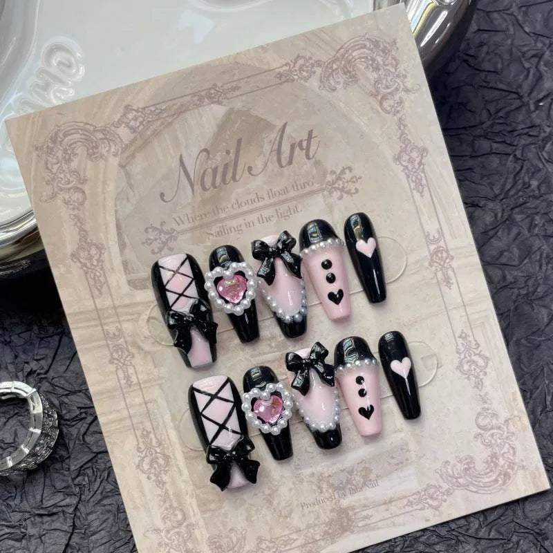 Hand-painted black and peach heart-shaped press-on nails with a cat's eye shine, shown in a set.